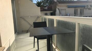 Een balkon met een tafel, stoelen, een droogrek en uitzicht op de omgeving.