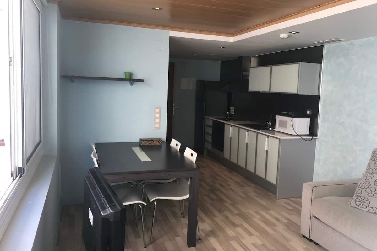 A compact living space with a dining area, kitchenette, and a sofa.