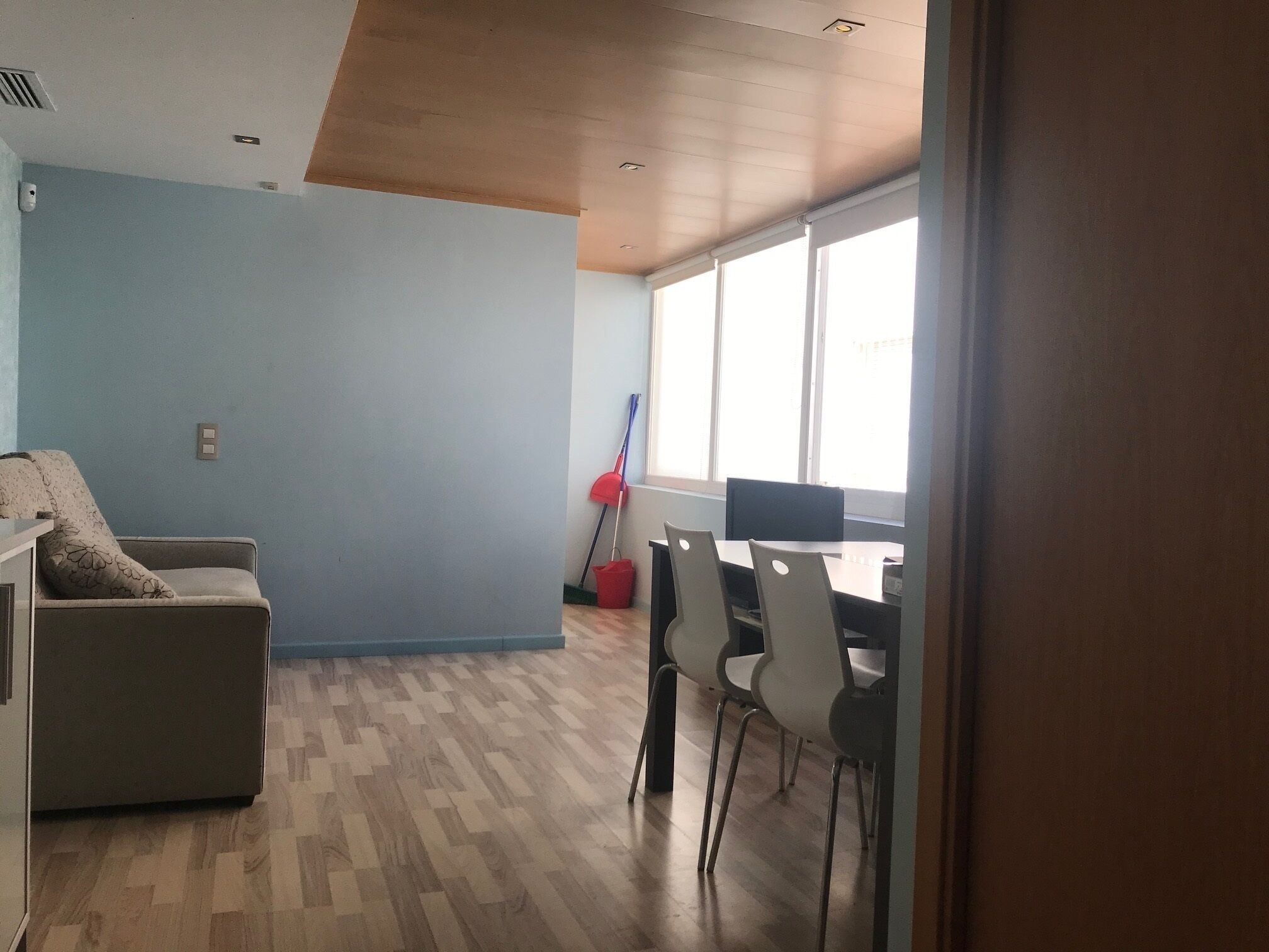 Una habitación con una mesa de comedor, sillas, un sofá y una ventana con persianas.