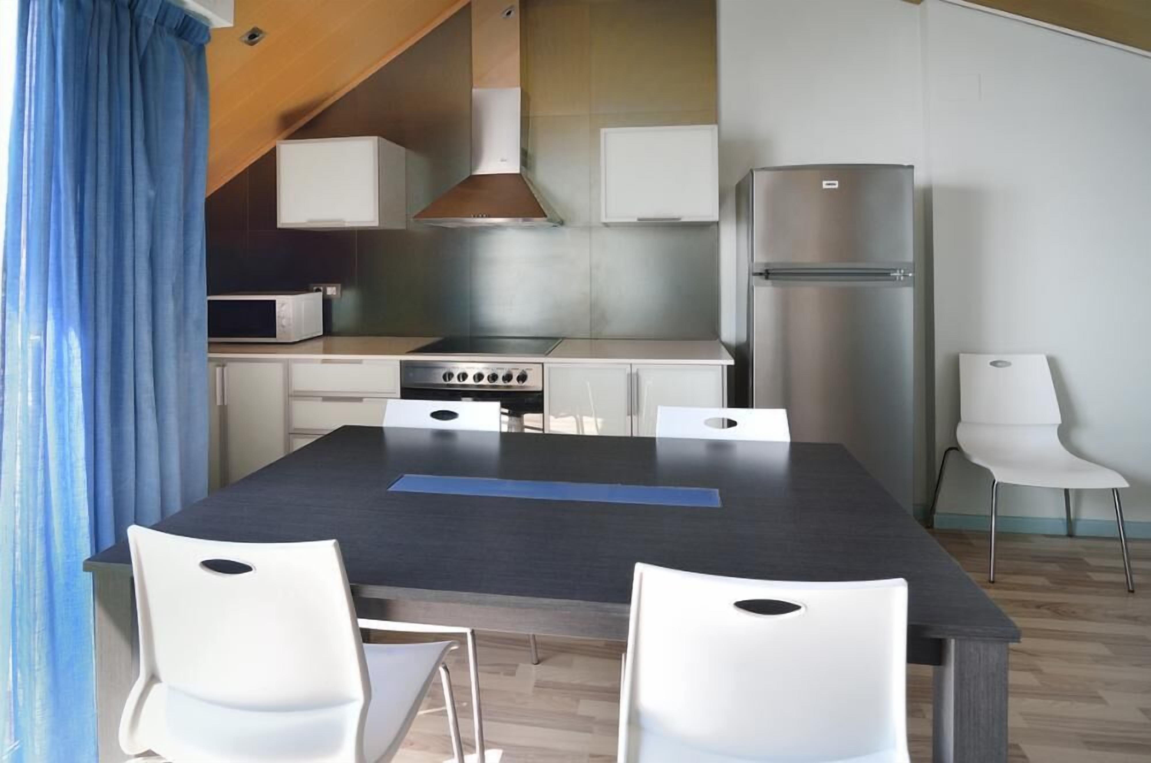 Una cucina moderna con isola centrale, mobili bianchi, frigorifero in acciaio inossidabile e forno a microonde.