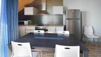 A modern kitchen with a central island, white cabinets, a stainless steel refrigerator, and a microwave.