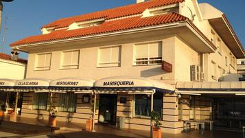 En bygning med et tag af fliser og flere butikker, heriblandt en restaurant ved navn 'MARISQUERIA'.
