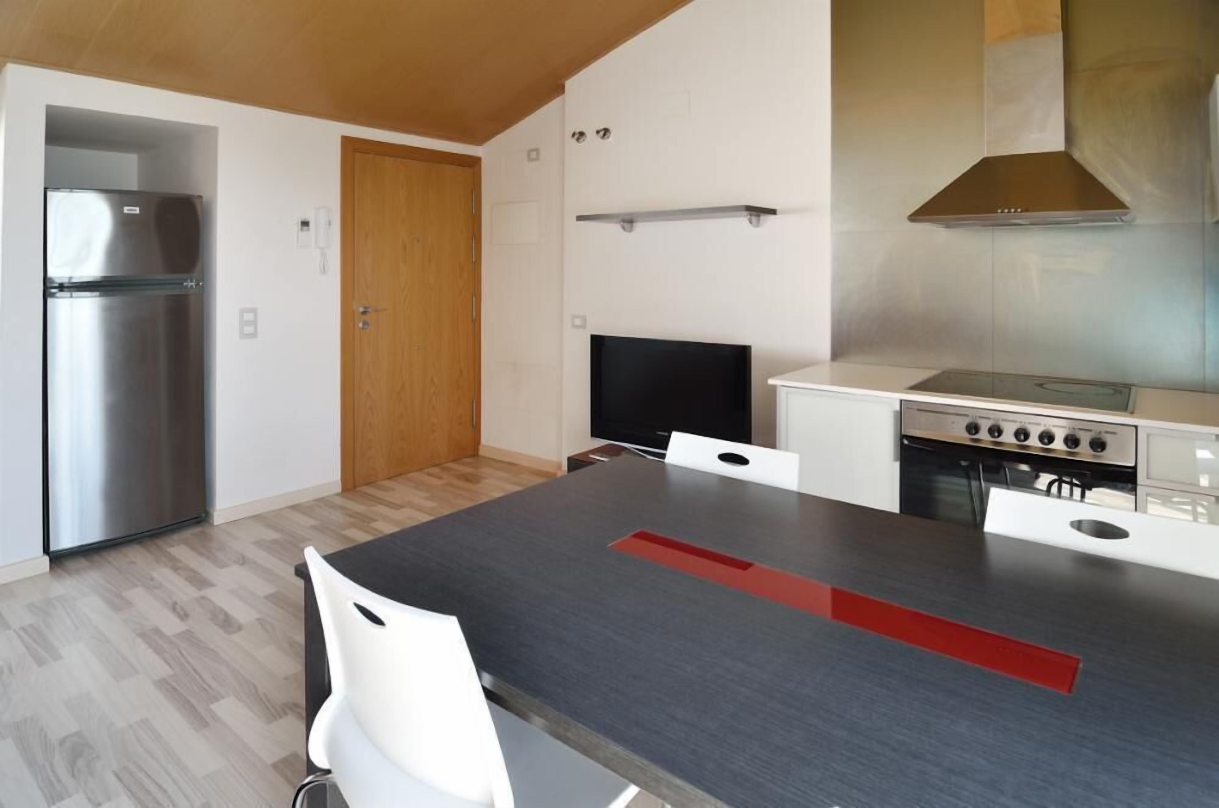 Eine moderne Küche mit einem Edelstahlkühlschrank, einem Flachbildfernseher und einem Gasherd.