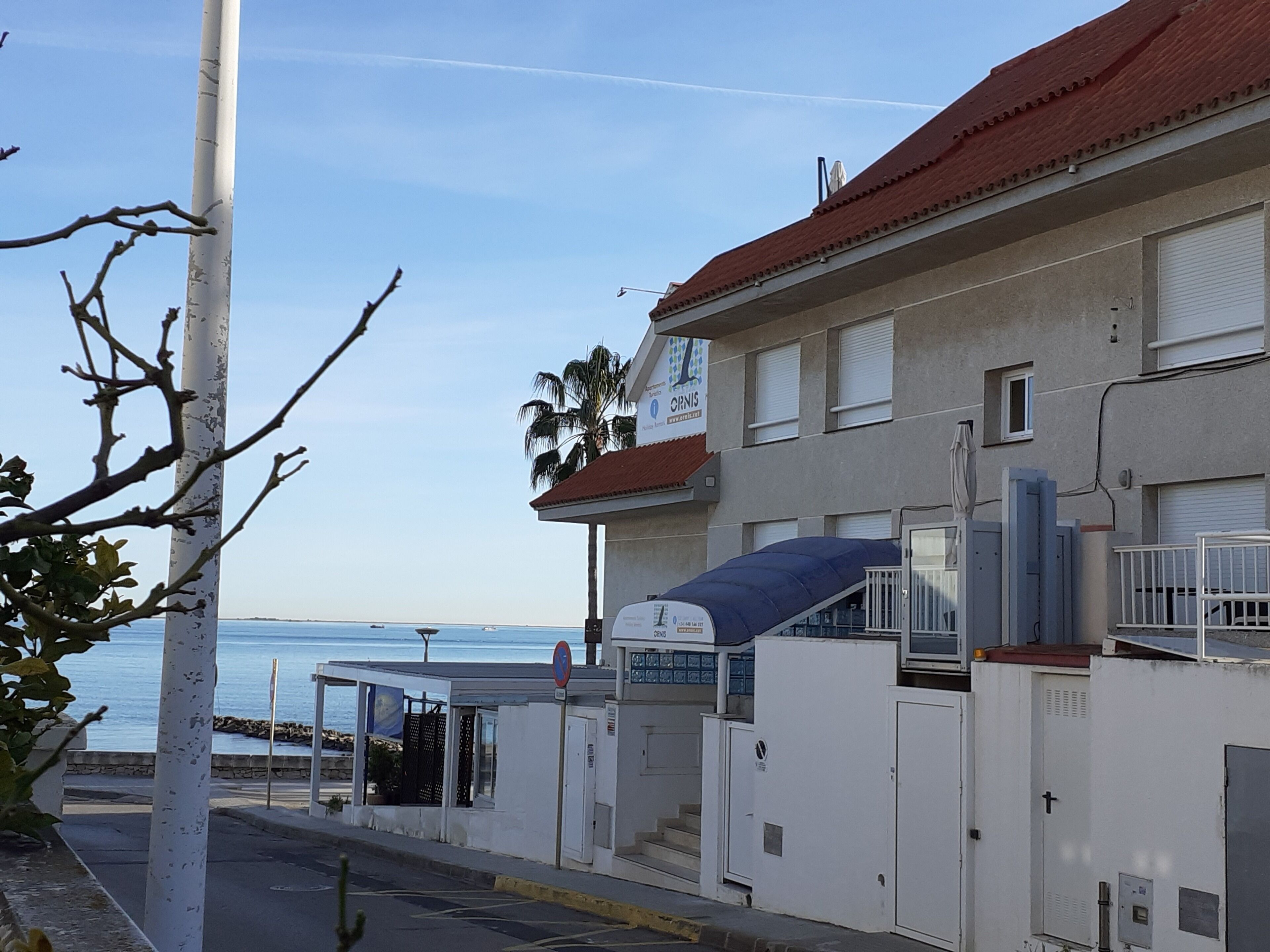 A coastal building with a red roof, a signboard, and a view of the sea.