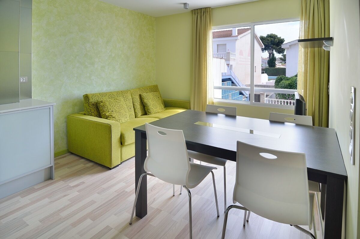 A modern living room with a sofa, a dining table, and chairs.