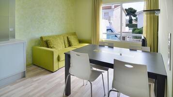 A modern living room with a sofa, a dining table, and chairs.