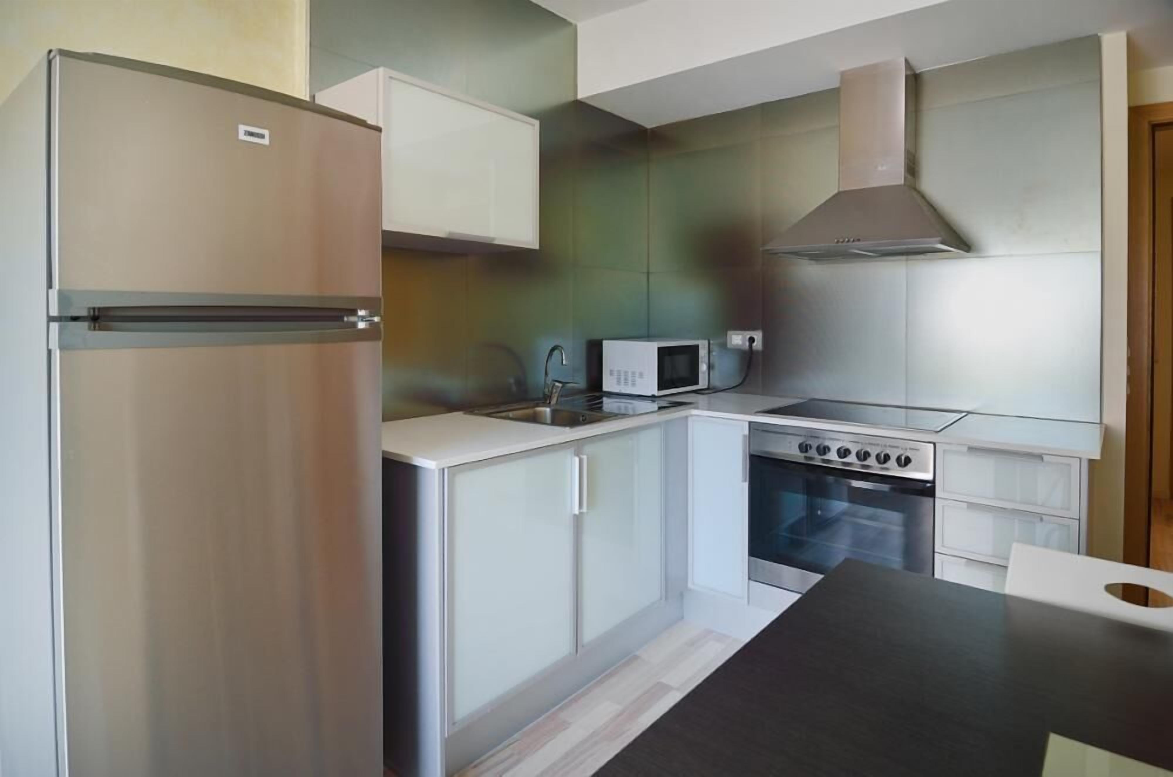 A compact kitchen with a refrigerator, microwave, stove, and cabinets.