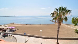 A beach with a palm tree, a covered area, and a parked motorcycle. - Apartamentos Ornis (Sant Carles de la Rapita)
