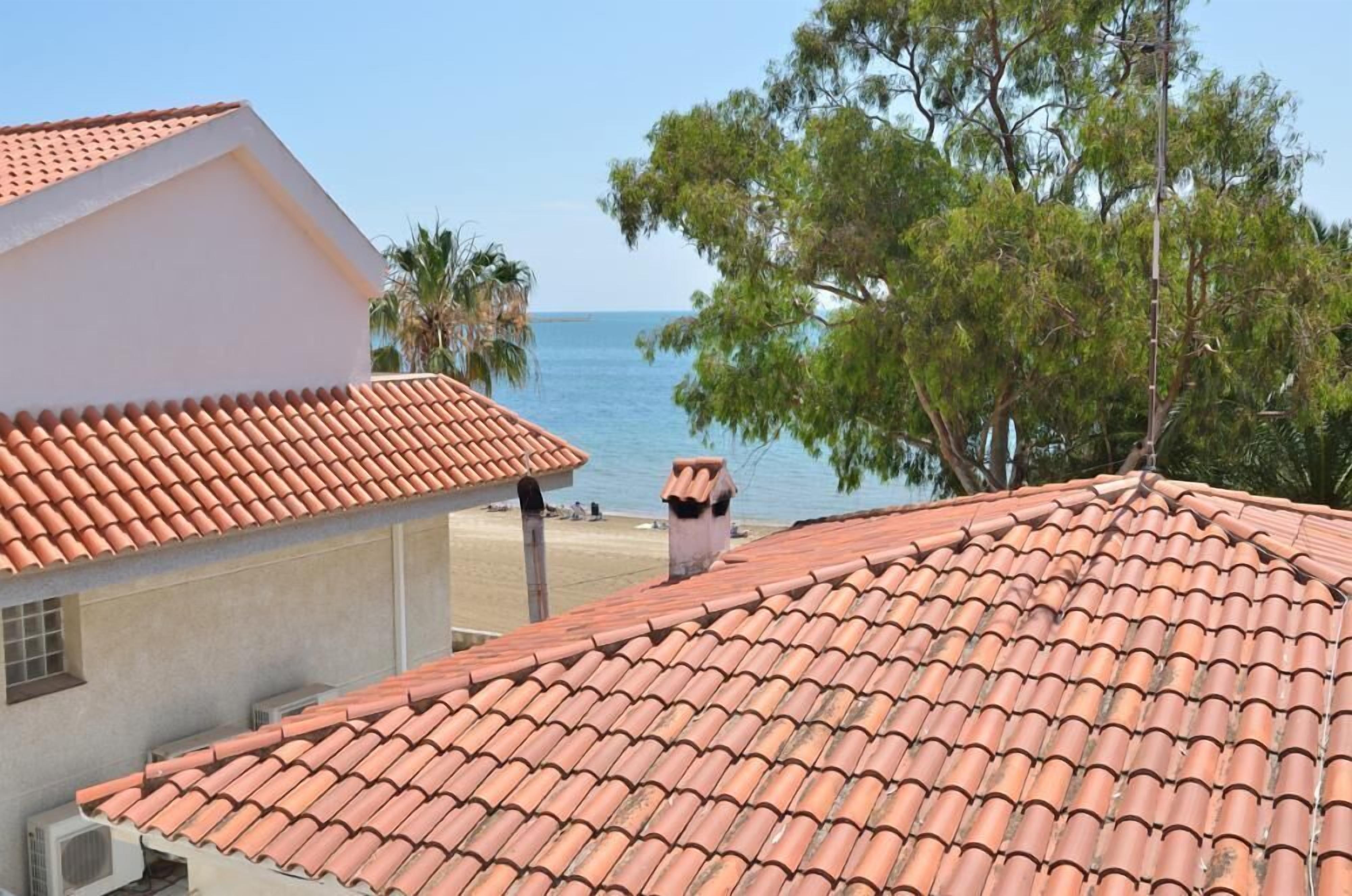 A coastal building with a red-tiled roof, a white exterior, and a view of the sea.