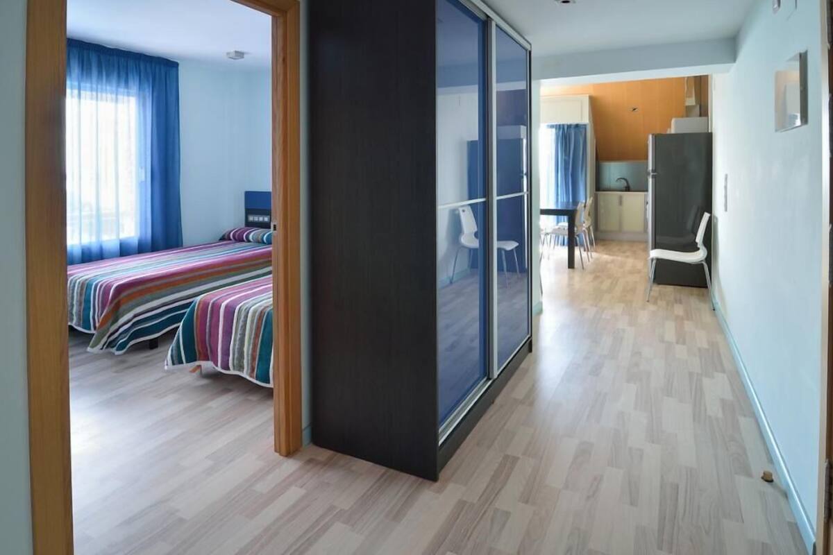 A modern hotel room with a large bed, a separate seating area, and a view through a sliding door.