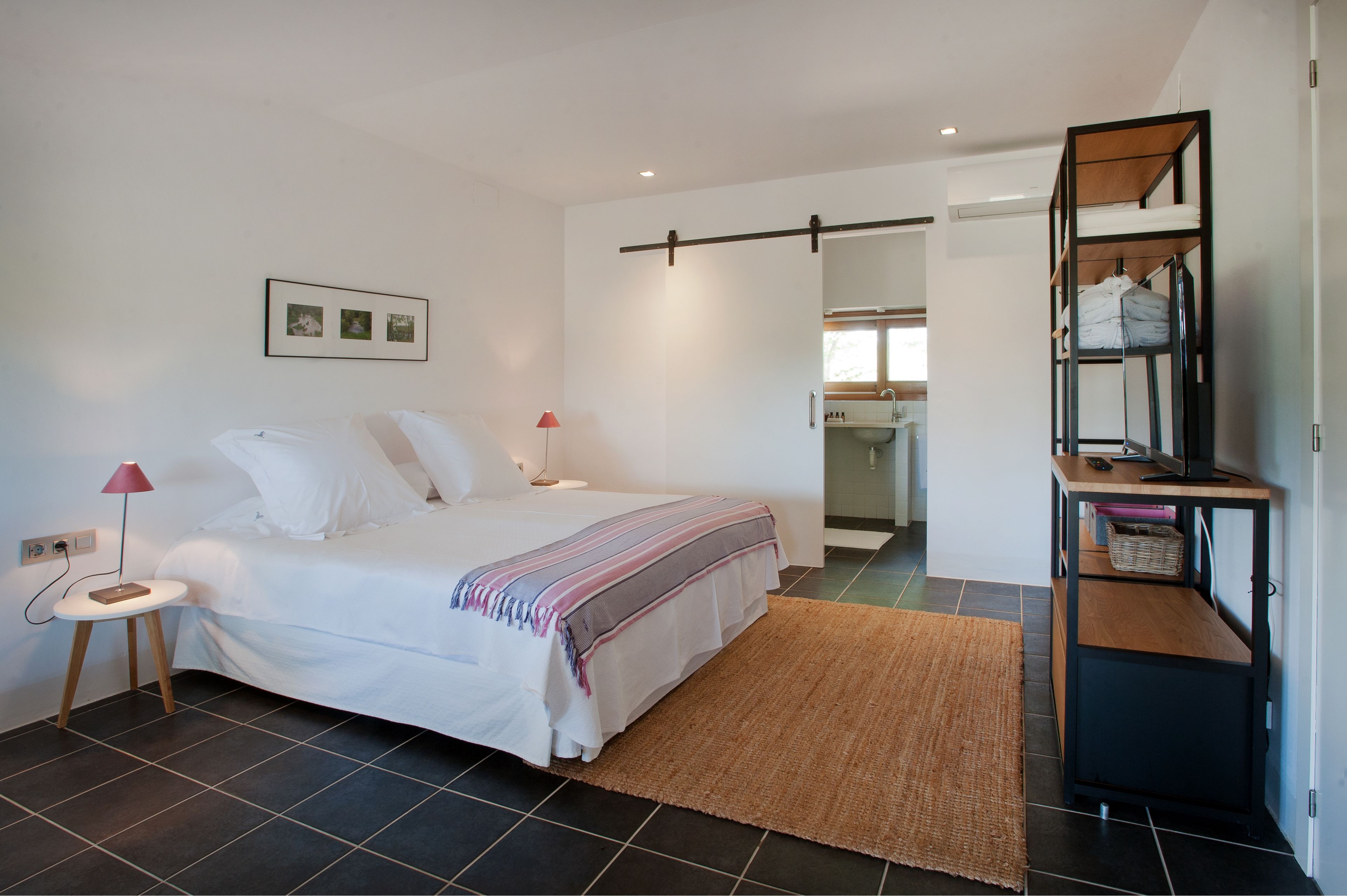 Een moderne slaapkamer met een bed, nachtkastjes, een bureau en een spiegel.