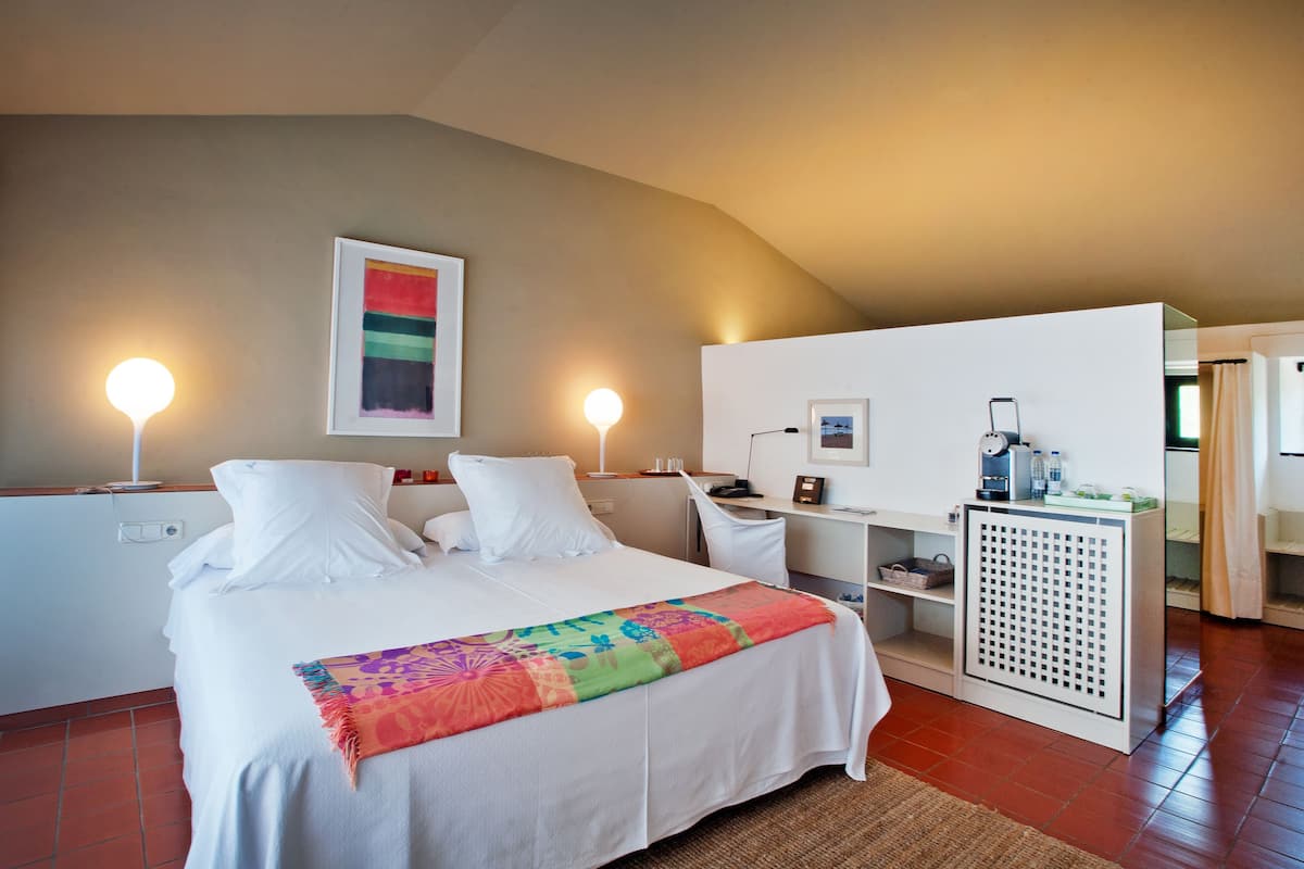 Une chambre d’hôtel avec un lit, des tables de chevet, un bureau et un radiateur.