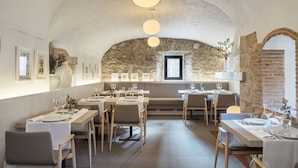 A restaurant with a stone archway, wooden tables, and a high ceiling with hanging lights. - Mas Falgarona Hotel Boutique and Spa (Avinyonet de Puigventos)