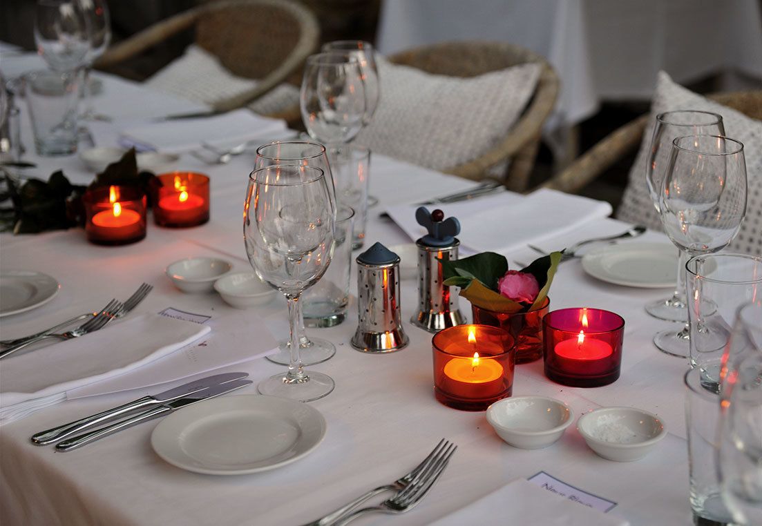 Una mesa lista para una comida, con velas, copas y cubiertos.