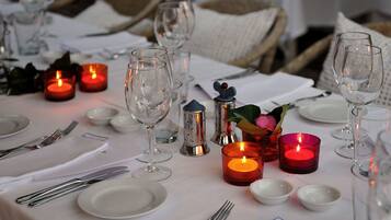Una mesa lista para una comida, con velas, copas y cubiertos.