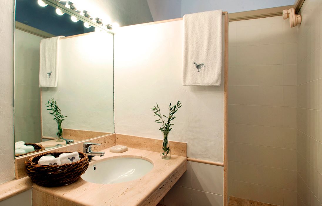 A bathroom with a sink, mirror, and two towels hanging on the wall.