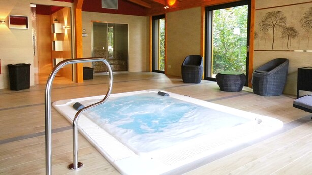 A spa area with a hot tub, wooden flooring, and wicker chairs. - Hotel Zum Leineweber (Burg (Spreewald))