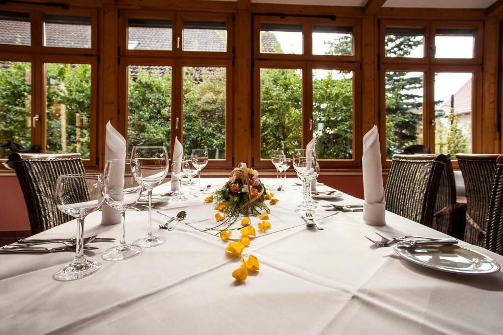 Een eettafel voor vier personen, gedekt met een wit laken, glaswerk en een middelpunt.