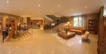 Un espacio habitable amplio con una escalera, un sofá, una mesa de centro y una estantería.
