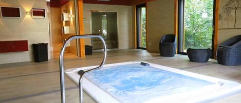 A spa area with a hot tub, wooden flooring, and wicker chairs.