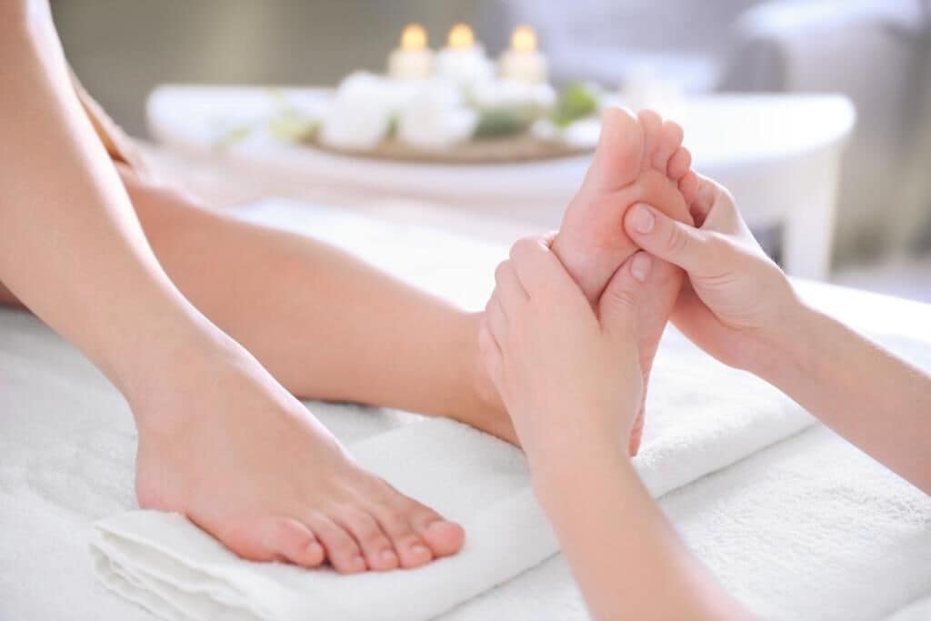 A foot massage with a foot resting on a towel and hands holding the foot.