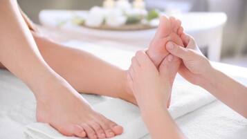 A foot massage with a foot resting on a towel and hands holding the foot.