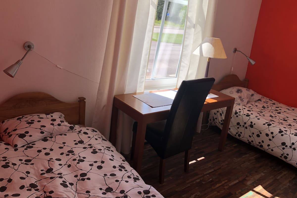 A room with two beds, a desk, and a chair.