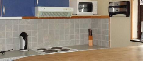 A kitchen with blue cabinets, a microwave, a toaster, and a clock on the wall.