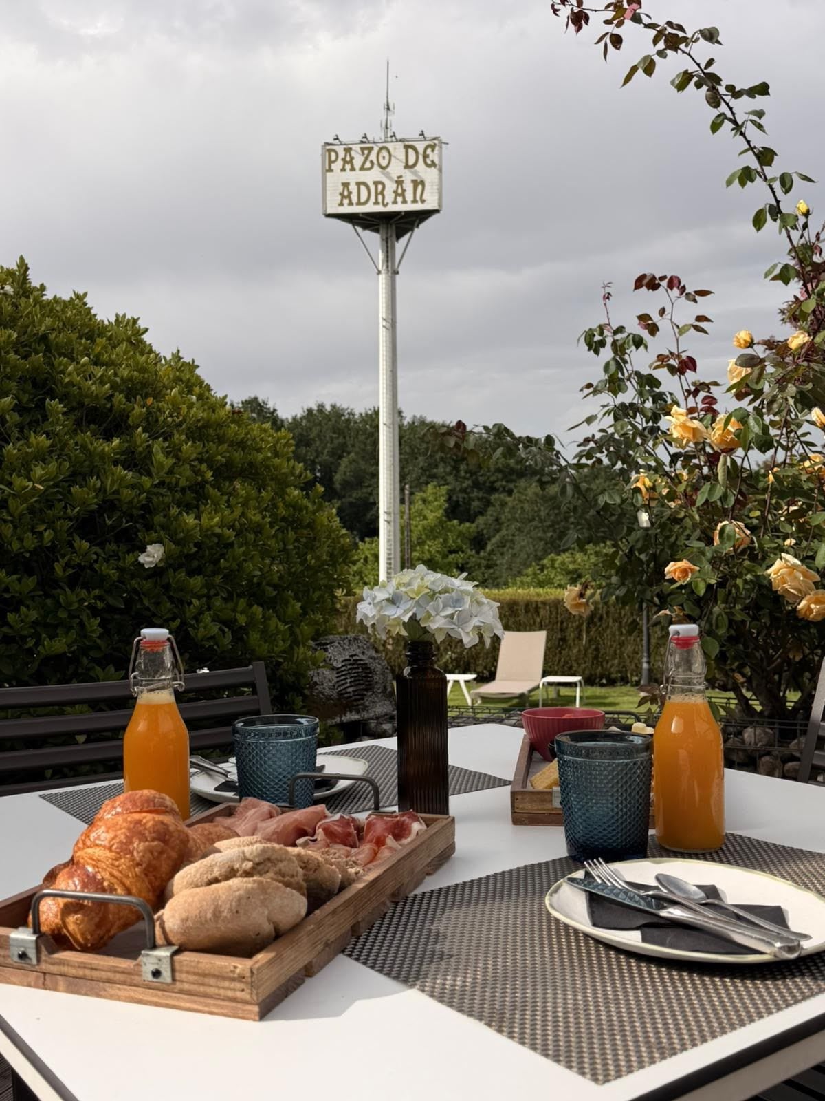 Disposición para comer al aire libre, con una mesa, comida, bebidas y un letrero al fondo.