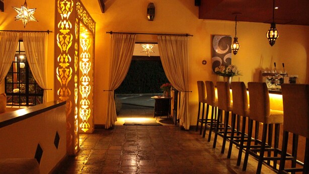 Um corredor pouco iluminado com um candeeiro em formato de estrela, parede estampada e vista para o exterior à noite.