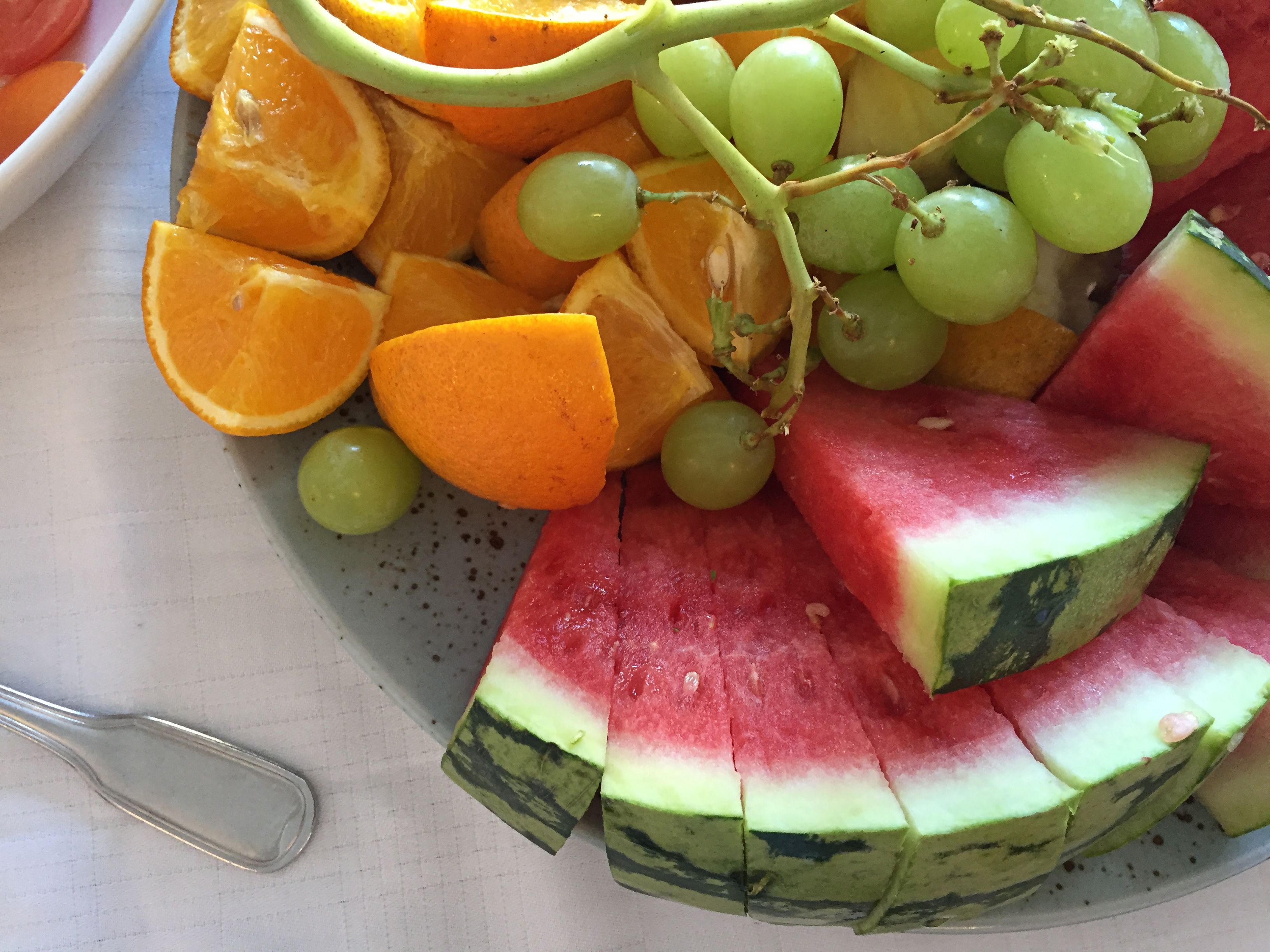 A plate of sliced watermelon, oranges, and grapes.