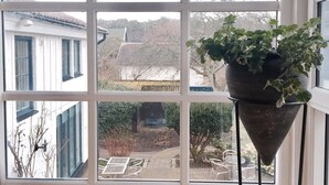 A window with a view of a garden and a building across the street. - Hotell Spelabäcken (Skanör)