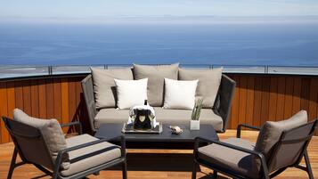 Una terraza con un sofá y dos sillones, una mesa de centro y una planta en maceta.