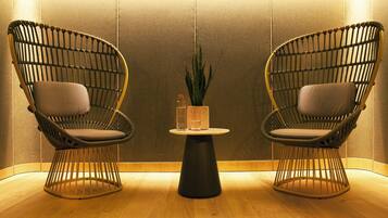 Two wicker chairs with cushions, a small round table with a plant, and a vase.