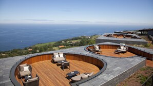 A rooftop terrace with curved wooden decking and outdoor furniture, overlooking a coastal landscape. - Akelarre - Relais & Châteaux (San Sebastián)