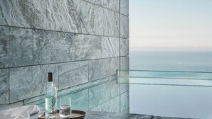 A bathroom with a stone wall and a wooden ceiling. A bottle and glass are on a tray on the wall. - Akelarre - Relais & Châteaux (San Sebastián)