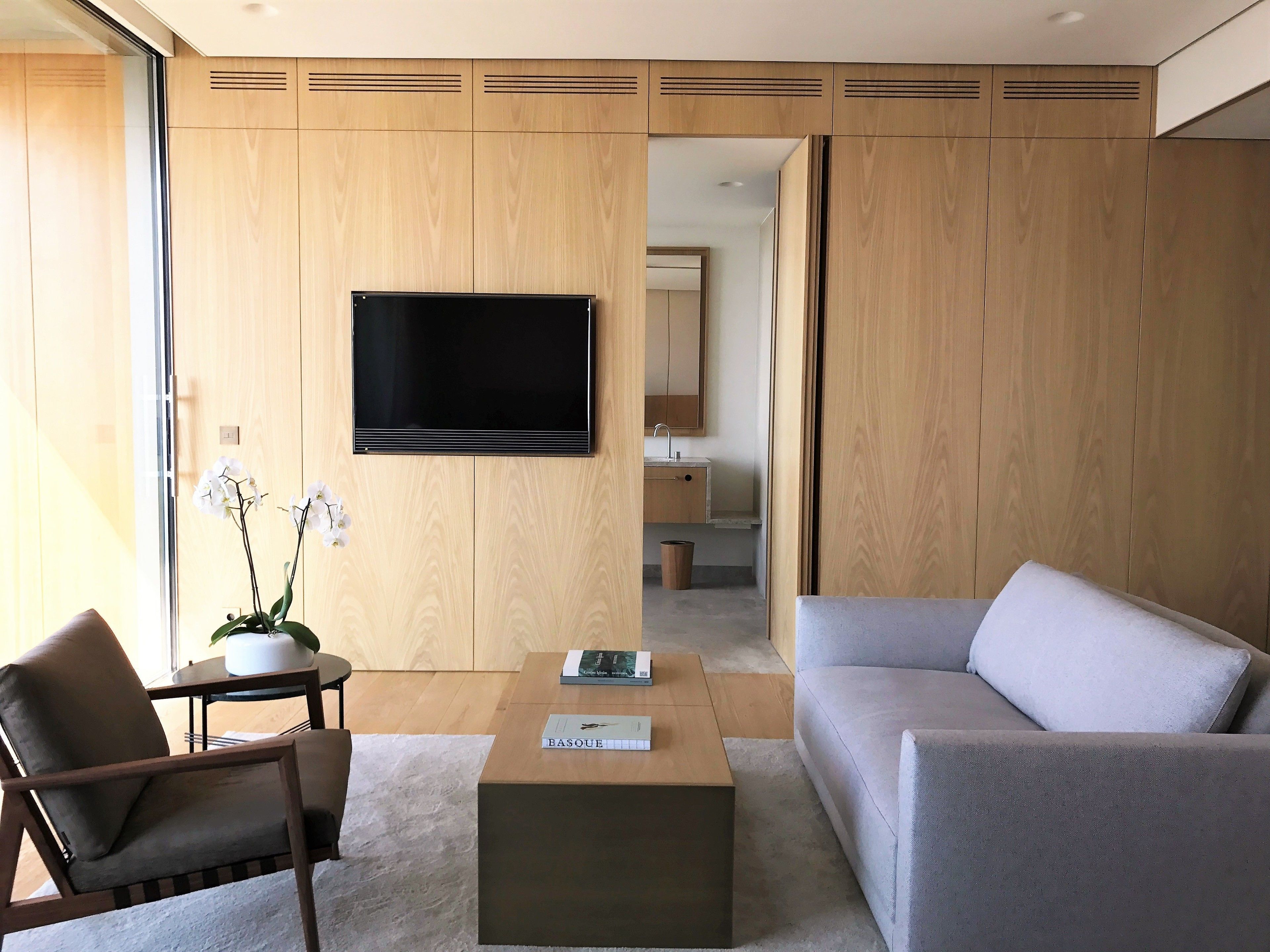 Een moderne woonkamer met een flatscreen televisie, een bank, een salontafel en een stoel.