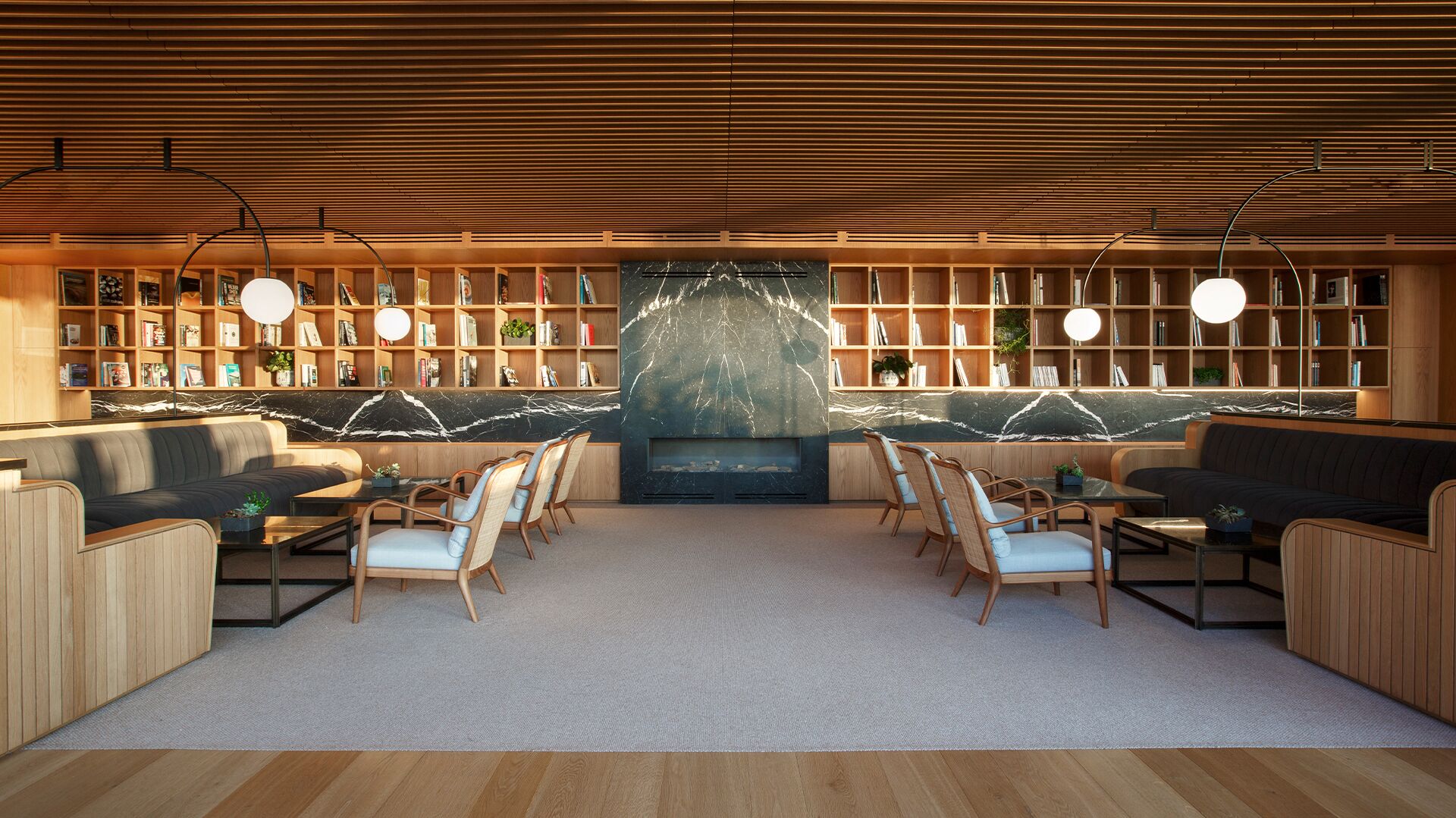 Una biblioteca moderna con estanterías de madera, asientos cómodos y una gran chimenea de mármol.