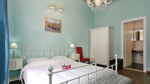 A bedroom with a bed, bedside tables, a red chair, a wardrobe, and a bathroom visible through an open door. - Scala Garden B&B (Florence)