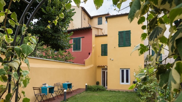 A courtyard with a table and chairs, a door, and a small garden area. - Scala Garden B&B (Florence)