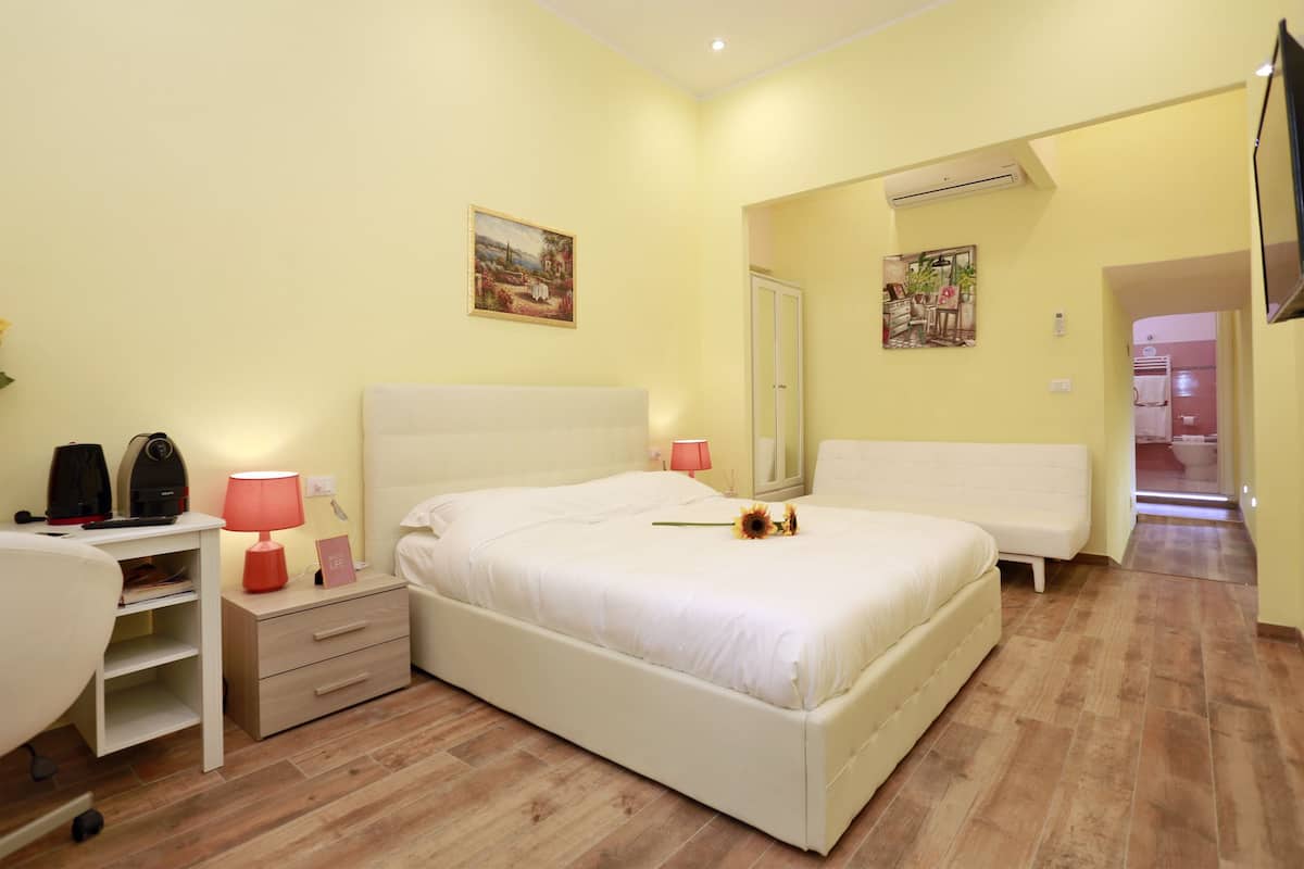 A bedroom with a bed, bedside tables, a desk, and a chair.