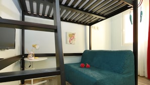 A room with a teal sofa, a small white table with a lamp, and a painting on the wall. - Scala Garden B&B (Florence)