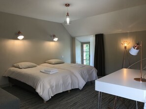 Habitación de hotel moderna con una cama grande, un escritorio y vistas a zonas verdes por la ventana.