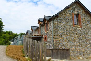 Ein Steinhaus mit Holzzaun und einer Treppe, die zu einem Balkon führt.