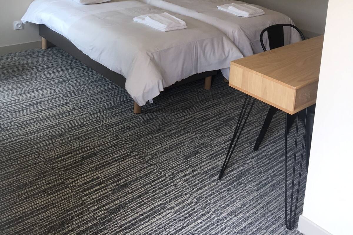 Hotellihuone, jossa on sänky, kaksi yöpöytää, työpöytä ja tuoli.
