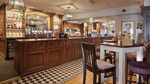 A bar area with wooden cabinets, a checkered floor, and hanging light fixtures. - Ye Olde Griffin (March)
