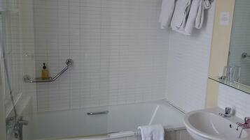 A bathroom with a shower, a sink, and a towel rack.