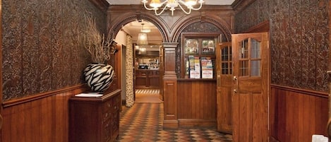 A hallway with patterned flooring, wooden walls, and a chandelier.