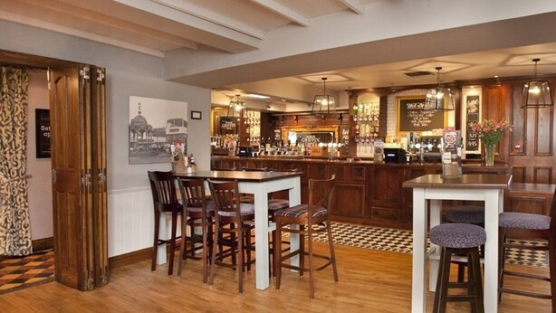 A spacious kitchen with a central island, bar area, and a dining set. - Ye Olde Griffin (March)