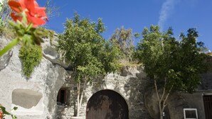 A stone building with a large wooden door, a small window, and a stone bench. - Kostantakis Winery & Residence (Milos)